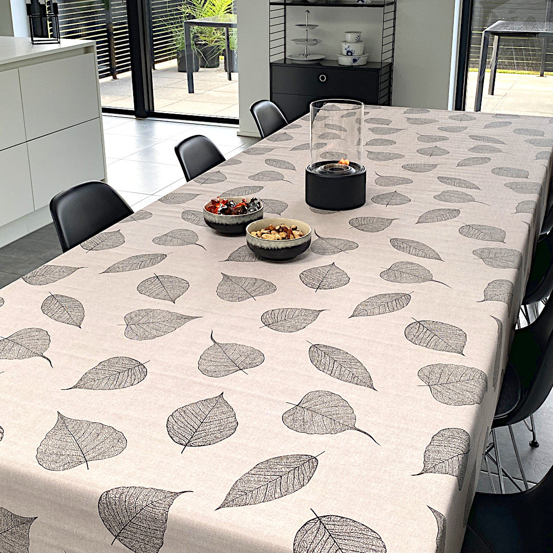 Voksduk med detaljerte sorte blader og hørlook på bord