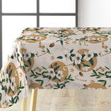 Råhvit julevoksduk med juleroser, kongler og gullmønster på bord