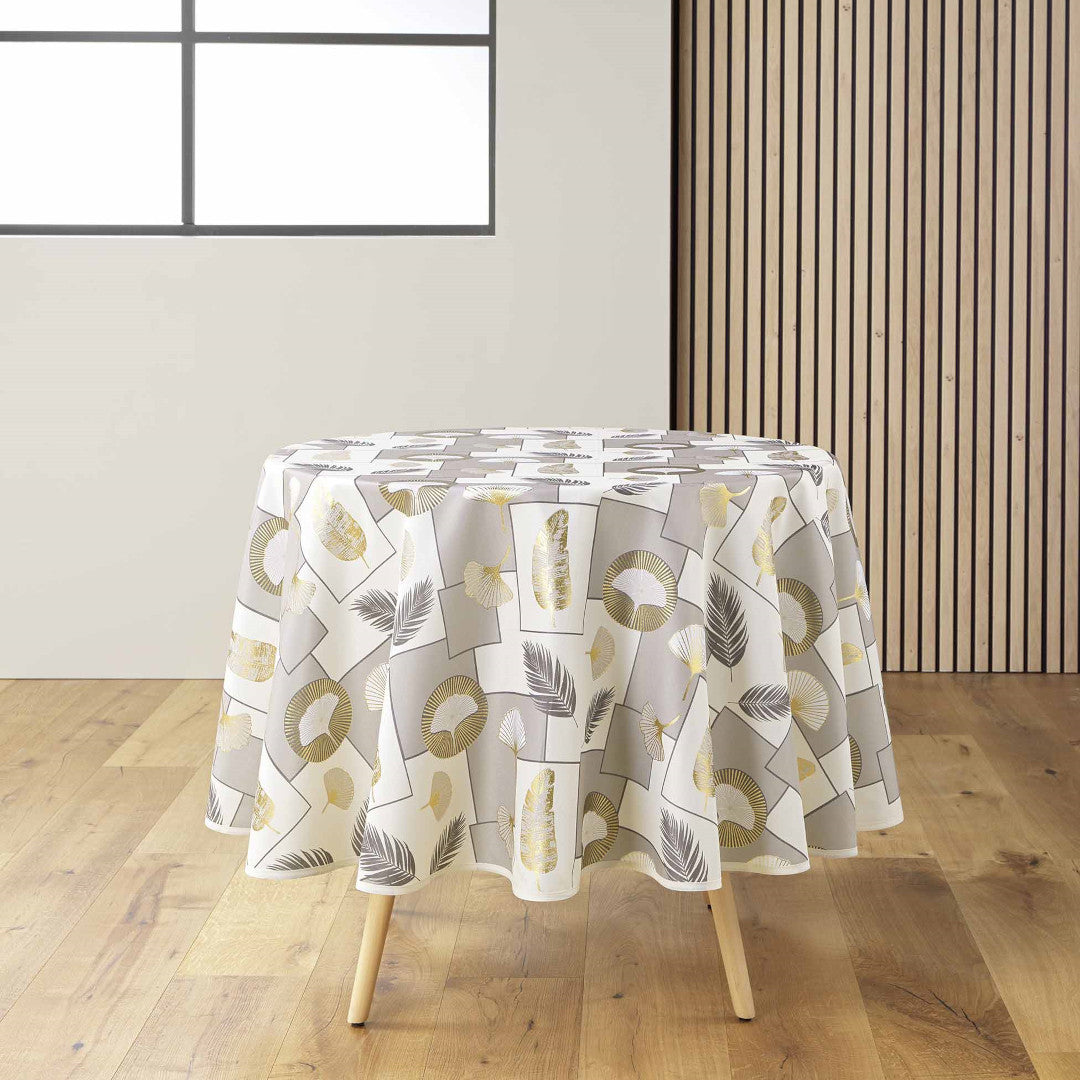 Natane Natural rund duk med bladmønster i gull og grått på en lys bakgrunn